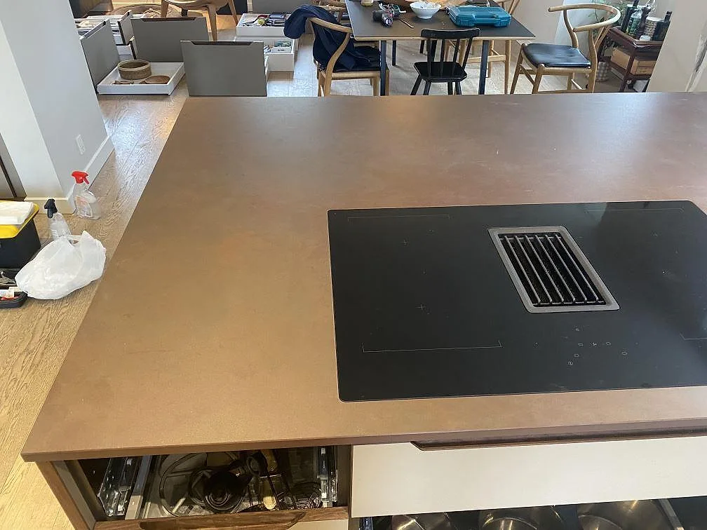 Köksö i Dekton Kadum, matt keramik, med induktionshäll med integrerad fläkt i ett kök i Valby.