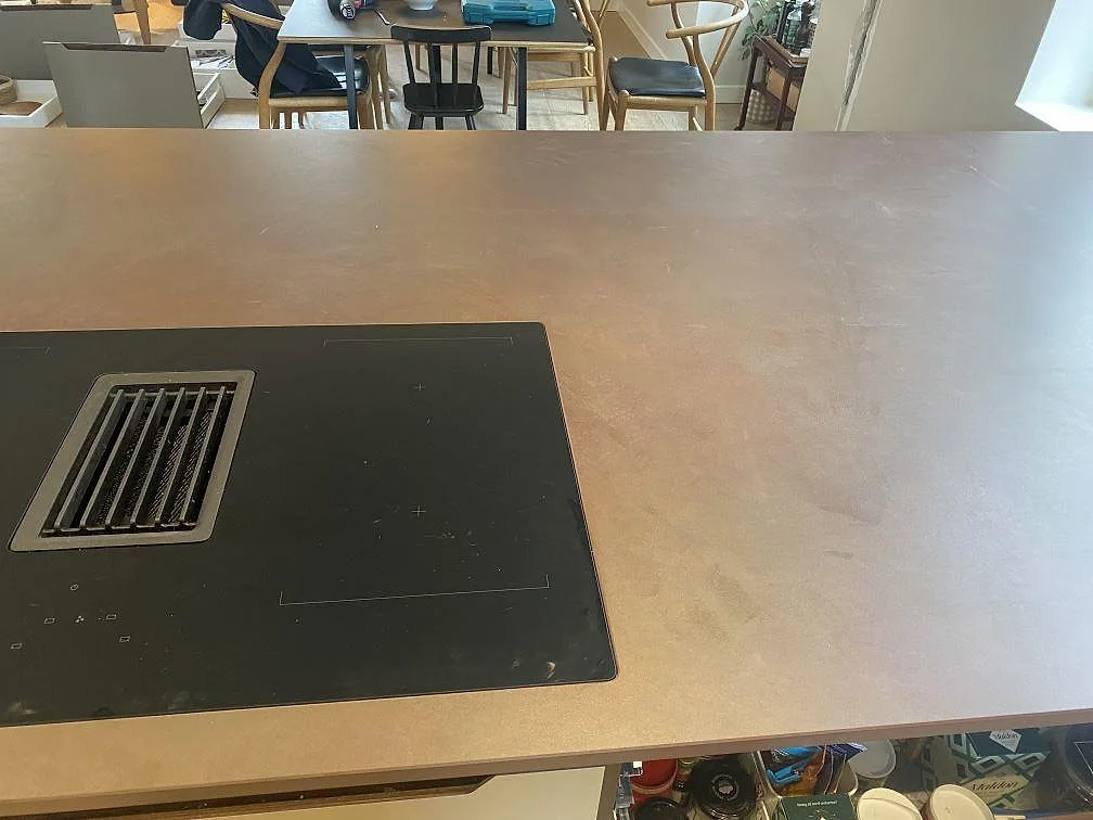 Detalj av induktionshäll med inbyggd fläkt i en köksö av Dekton Kadum, matt beige keramik, i Valby.