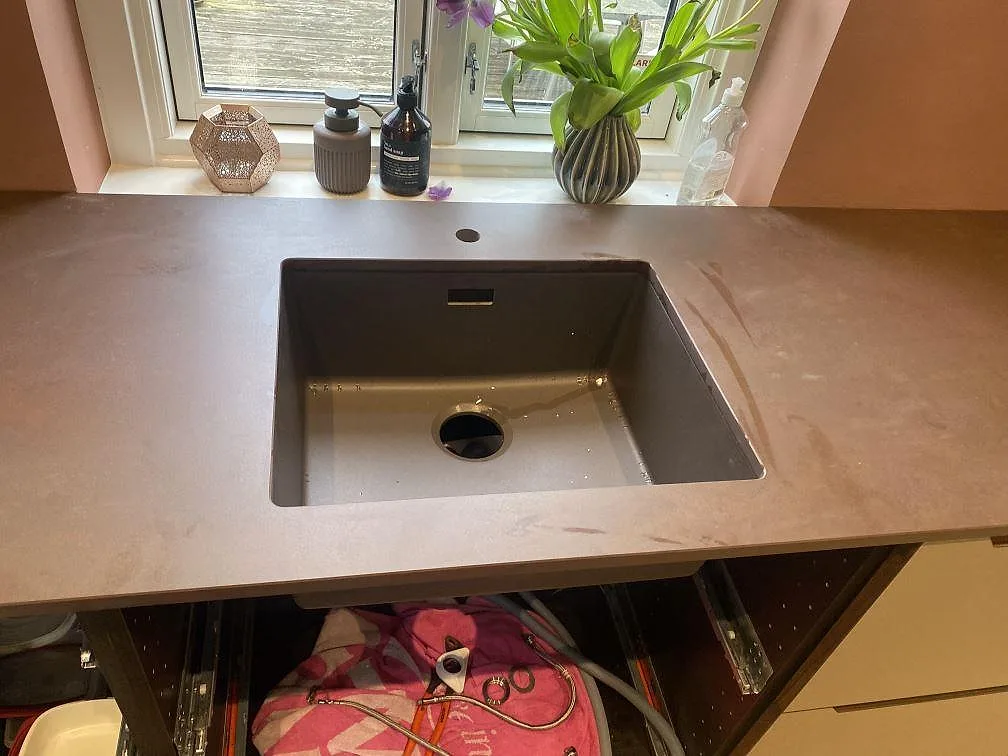 Underlimmad komposithoar i en köksbänkskiva i Dekton Kadum, matt beige keramik, i ett kök i Valby.