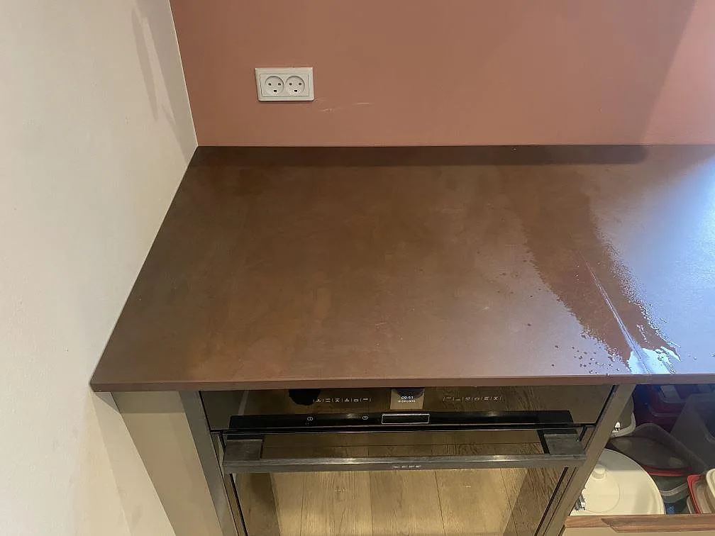 Köksbänkskiva i Dekton Kadum, matt keramik i varm beige, monterad mot terrakottafärgad vägg i ett kök i Valby.
