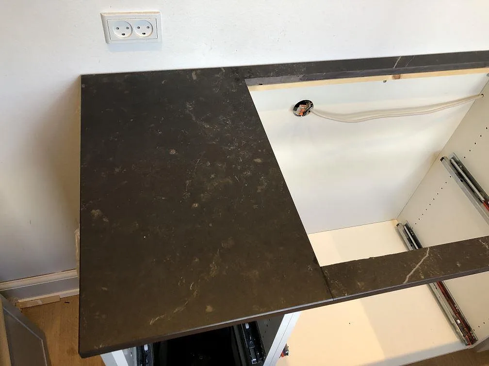 Mörk köksbänkskiva i Dekton Kelya monterad över öppna köksstommar under installation i Frederiksberg C.