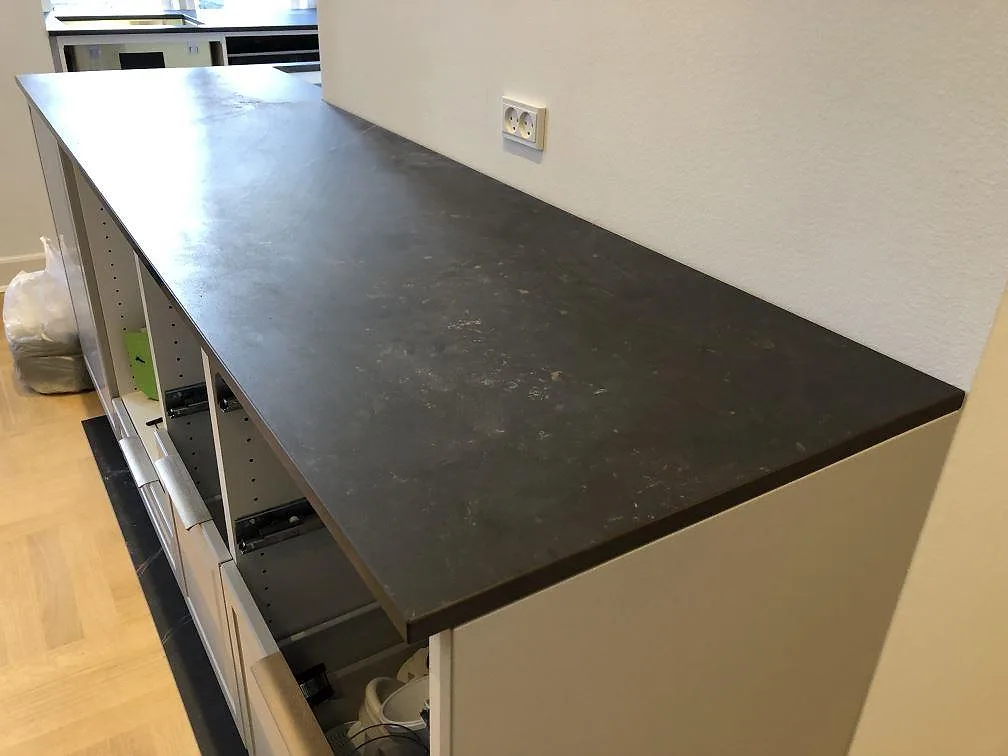 Köksö i Dekton Kelya, matt mörk keramik, monterad ovanpå köksstommar i ett kök i Frederiksberg C.