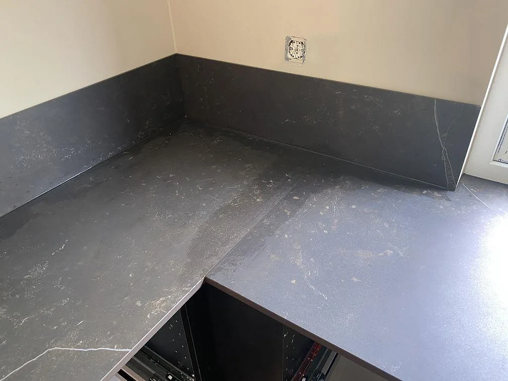 Vinkelmonterad köksbänkskiva i Dekton Kelya med uppvikt stänkskydd sett ovanifrån i ett kök i Genarp.