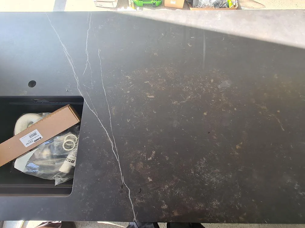 Närbild av matt Dekton Kelya keramik med ljus ådring och förberedd öppning i köksön i Glanshammar.