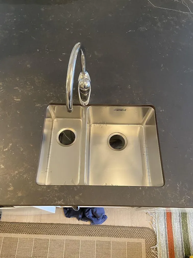 Köksbänkskiva i mörk Dekton Kelya, matt, med underlimmad rostfri diskho och köksblandare i ett kök i Göteborg.