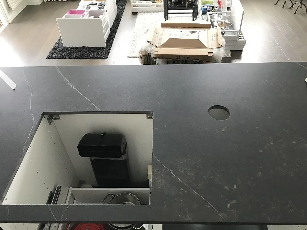 Detalj av ön i Dekton Kelya med urtag för häll, matt svart keramik i ett kök i Göteborg.