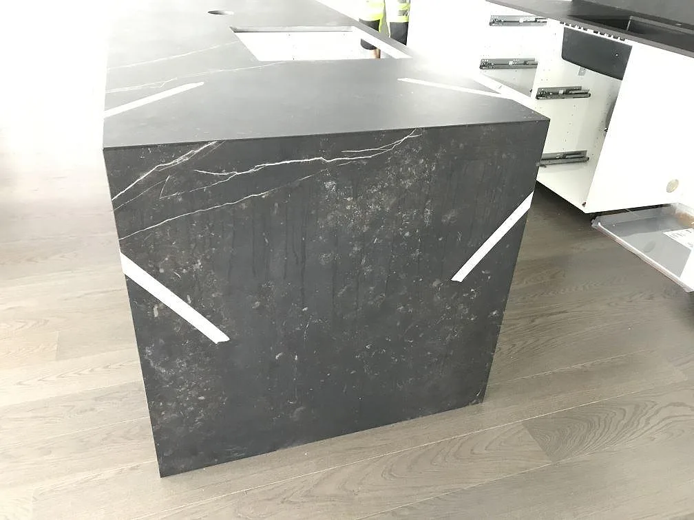 Köksö i svart Dekton Kelya med urtag för häll och avfallslucka, matt keramik i ett kök i Göteborg.