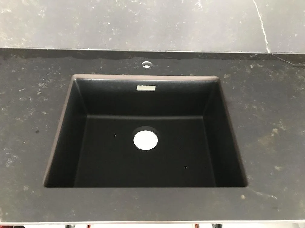 Underlimmad mörk diskho i köksbänkskiva av svart Dekton Kelya, matt keramik, i ett kök i Göteborg.