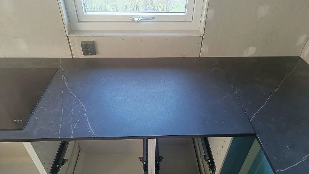 Matt Dekton Kelya bänkskiva med tydlig ljus ådring längs fönstret i ett kök i Hässleholm.