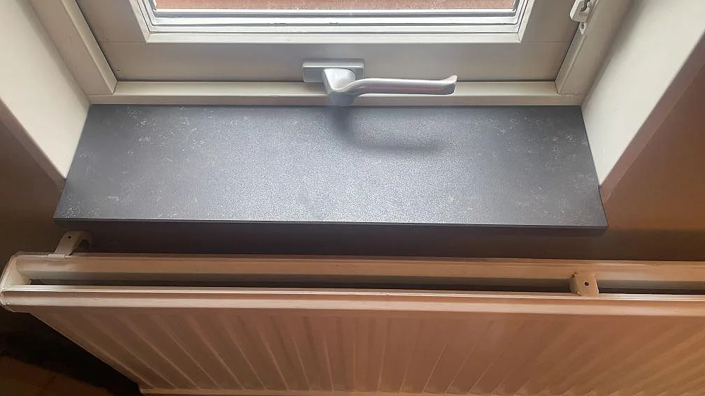 Fönsterbänk i matt Dekton Kelya monterad under fönster ovanför radiator i Helsingborg.