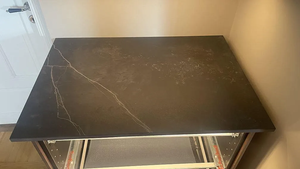 Rak bänkskiva i matt Dekton Kelya med ljus ådring ovanpå öppna mörka stommar i Helsingborg.