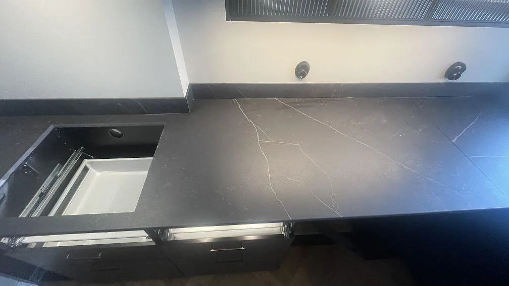 Mörk köksbänkskiva i matt Dekton Kelya med diskhoöppning och ljusa ådror under montering i Helsingborg.