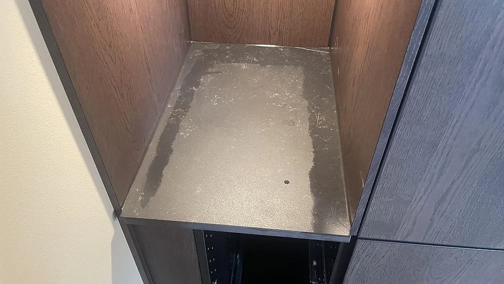 Mindre bänkskiva i matt Dekton Kelya monterad mellan träpaneler och mörka stommar i Helsingborg.