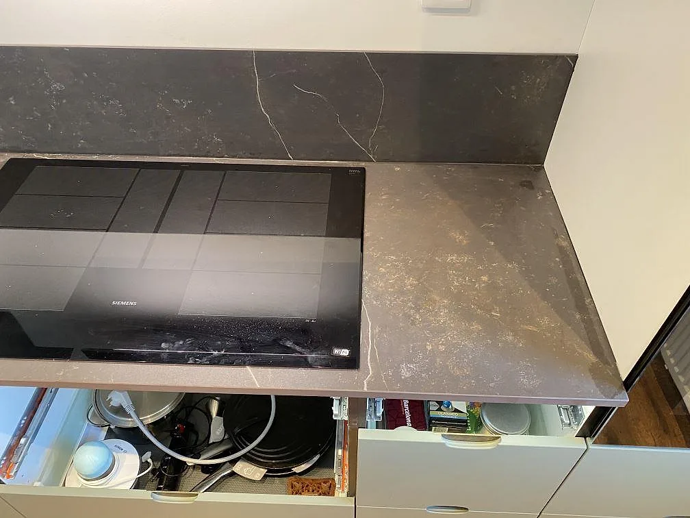 Bänk i mörkgrå Dekton Kelya med vit kompositdiskho och infälld häll i ett kök i Höör.