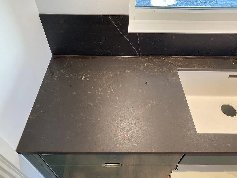 Infälld induktionshäll i mörkgrå Dekton Kelya köksbänkskiva med stänkkant i samma sten i ett kök i Höör.