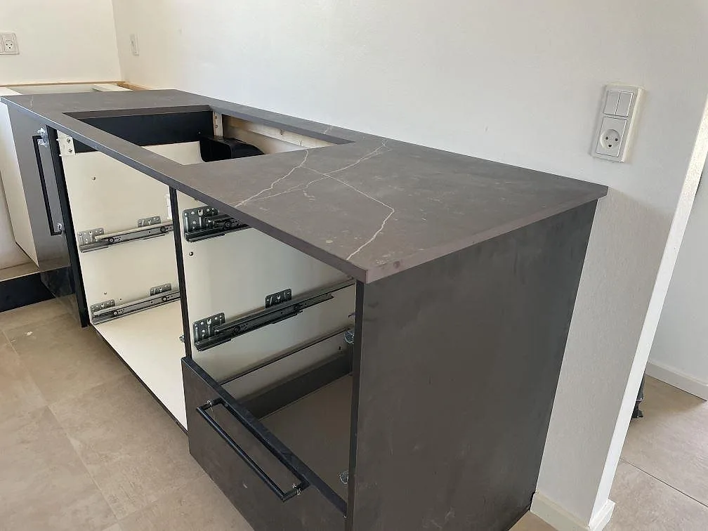 Väggbänk i matt Dekton Kelya med urtag för underlimmad diskho och mörkgrå stommar i ett kök i Hørsholm.