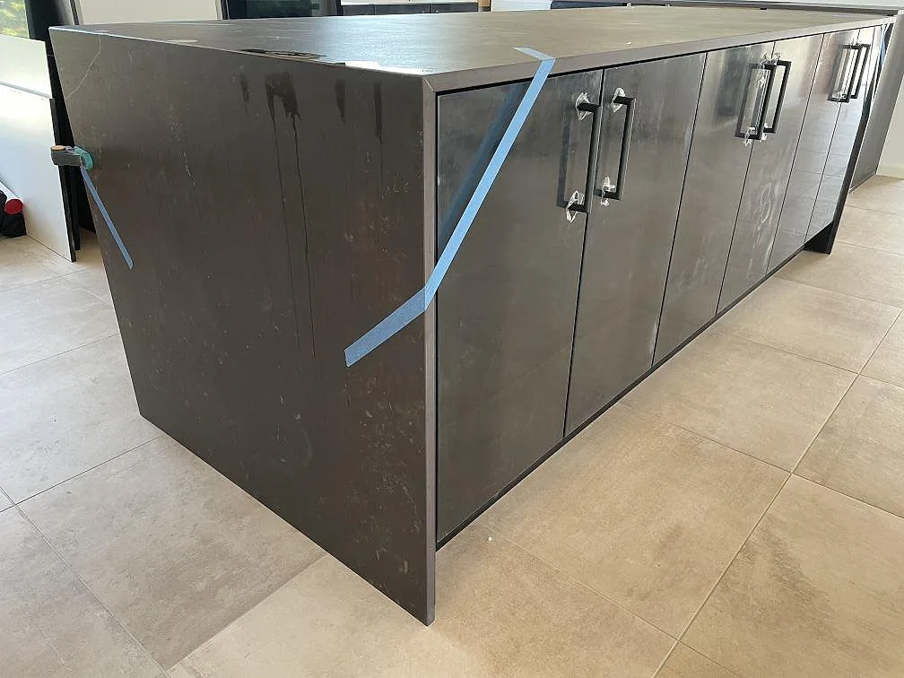 Dekton Kelya som matt keramisk köksbänkskiva på lång köksö med mörka skåp och ljus klinker i Hørsholm.