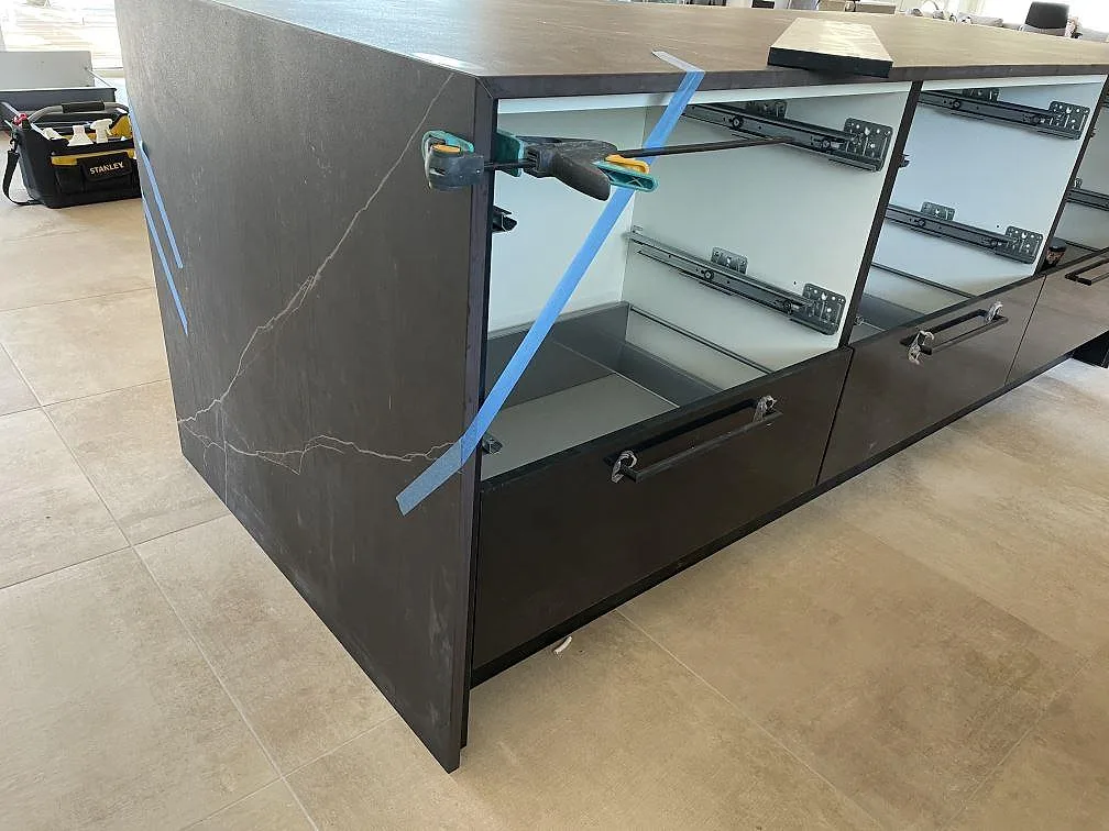 Närbild av köksö i matt Dekton Kelya med neddragen sida, synlig ljus ådring och monteringsverktyg i Hørsholm.