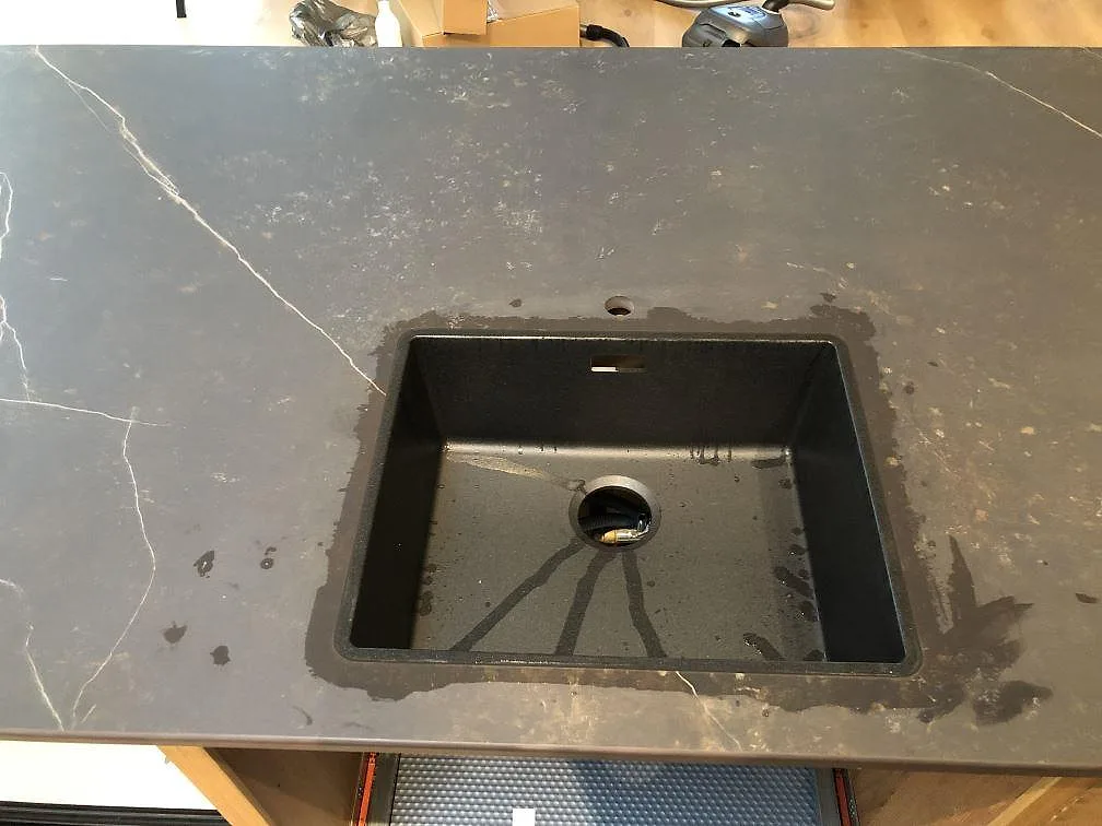 Underlimmad svart komposithoar i en köksbänkskiva av Dekton Kelya i matt keramik i ett kök i Hvidovre.