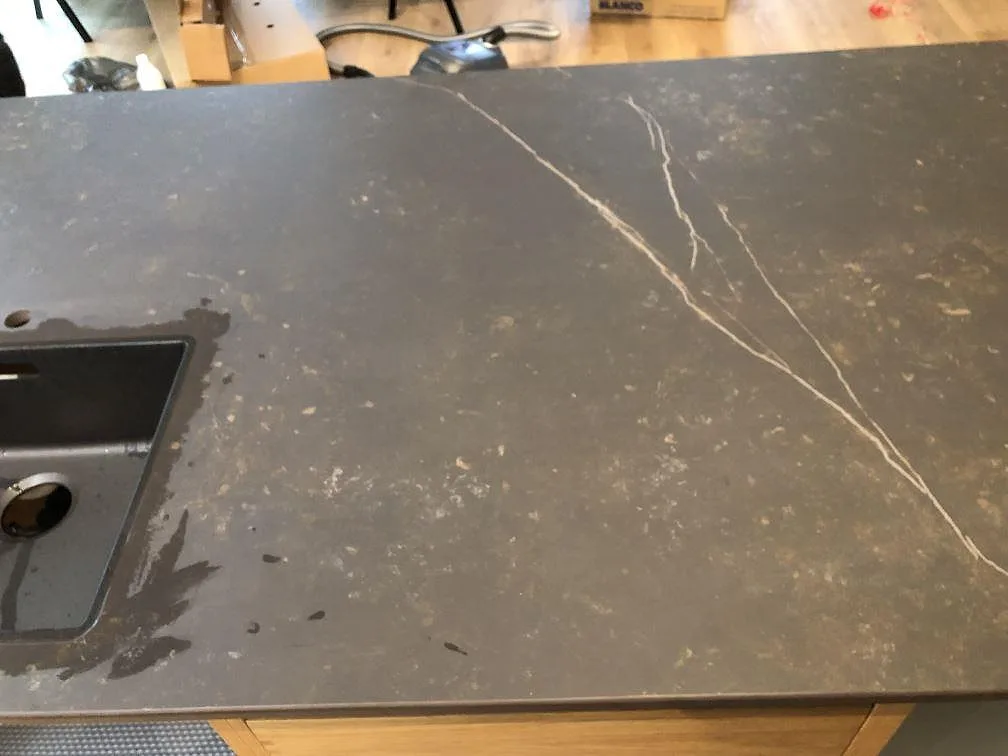 Köksbänkskiva i Dekton Kelya intill fönster med induktionshäll i matt keramik i ett kök i Hvidovre.