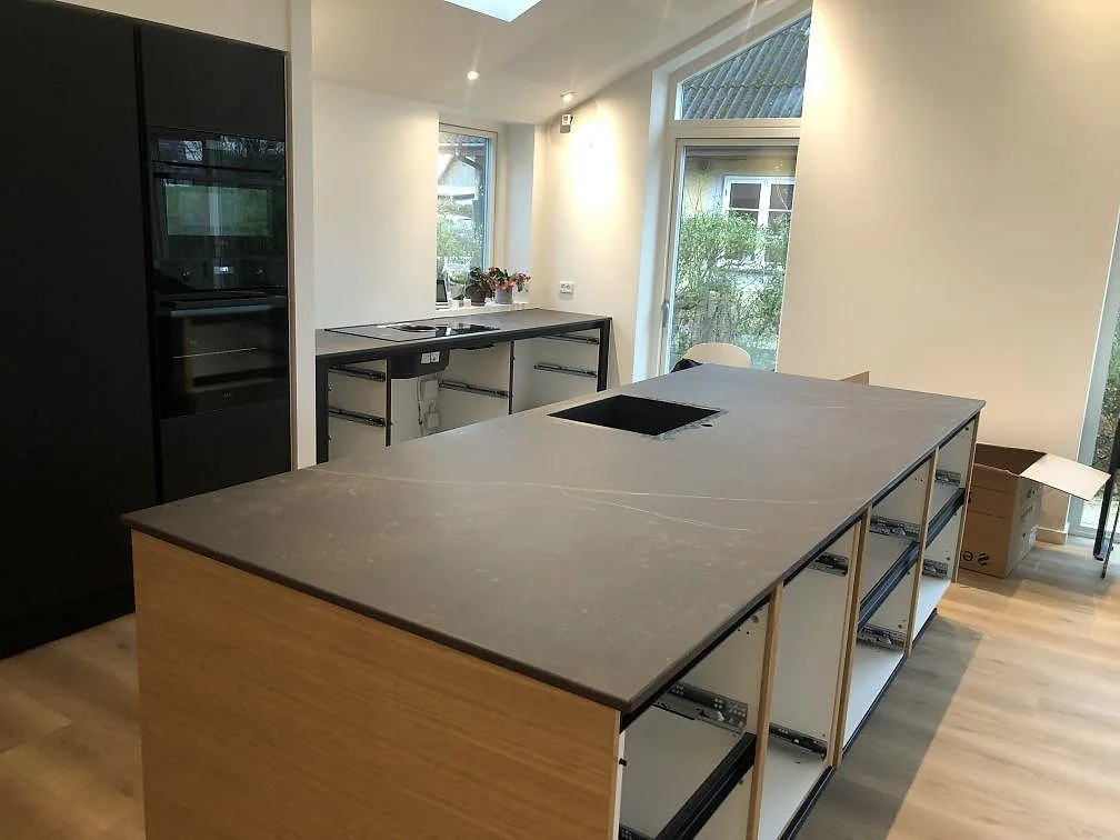 Perimeterbänk i Dekton Kelya i matt mörk keramik med underlimmad hoar i ett kök i Hvidovre.