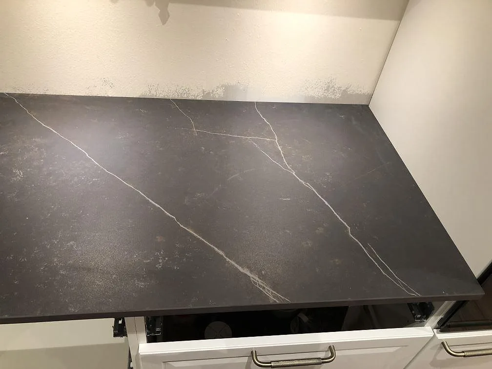 Närbild på bänkskiva i Dekton Kelya, matt, med vit ådring över vita köksluckor i Kärna.