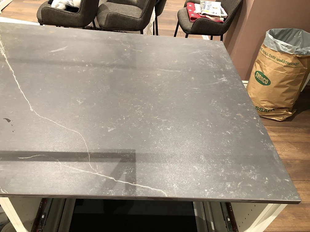 Köksö i mörkgrå Dekton Kelya, matt, med synlig ådring och monteringsmiljö i Kärna.