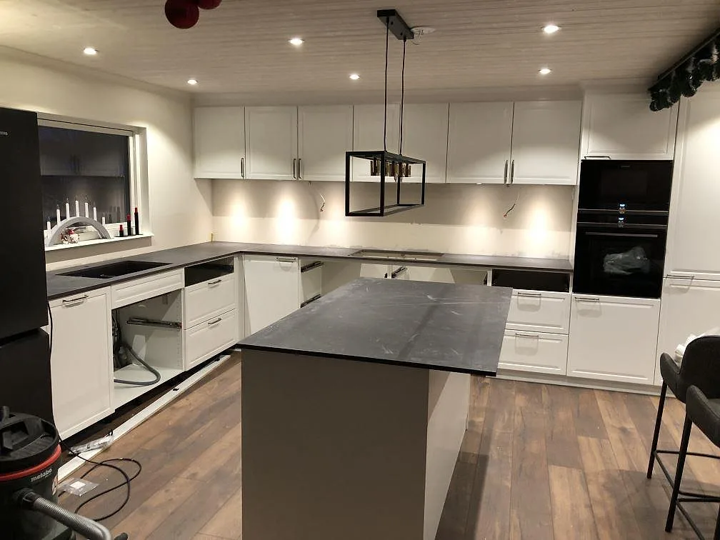 Köksbänkskiva och köksö i Dekton Kelya, matt mörkgrå keramik med ljus ådring, i ett kök under montering i Kärna.