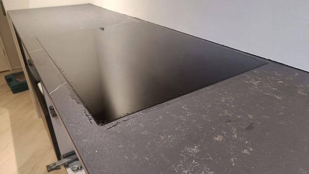 Närbild på svart häll monterad i en matt köksbänkskiva i Dekton Kelya i Kolding.