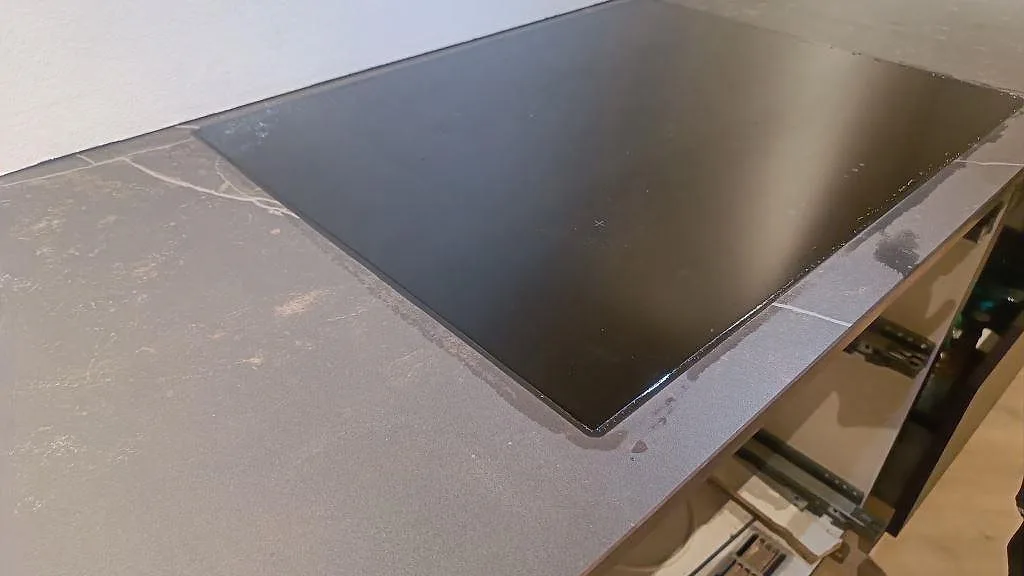 Detalj av svart häll och mörkgrå Dekton Kelya med ljus ådring i ett kök i Kolding.