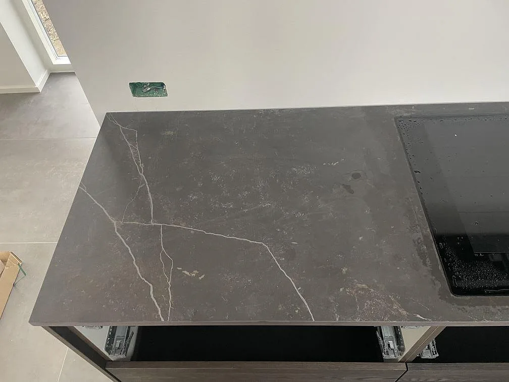 Bänkskiva i matt Dekton Kelya med vit ådring och infälld induktionshäll, sedd ovanifrån i ett kök i Kr.Hyllinge.