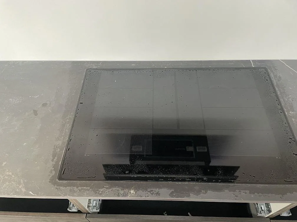 Mörkgrå Dekton Kelya köksbänkskiva med infälld induktionshäll i ett kök under montering i Kr.Hyllinge.