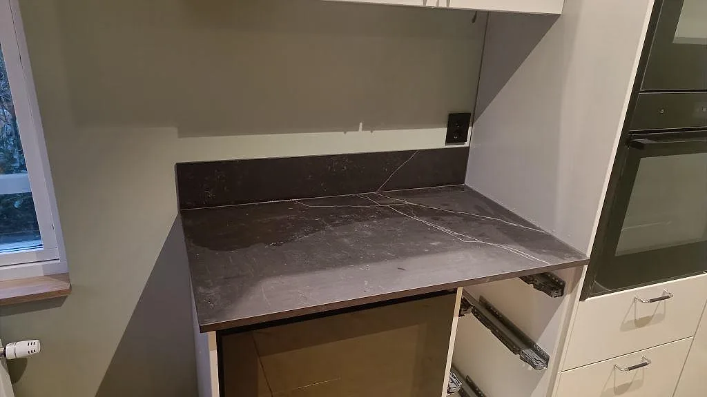 Arbetsyta i matt Dekton Kelya med stänkskydd under överskåp i ett kök under montering i Kungsbacka.