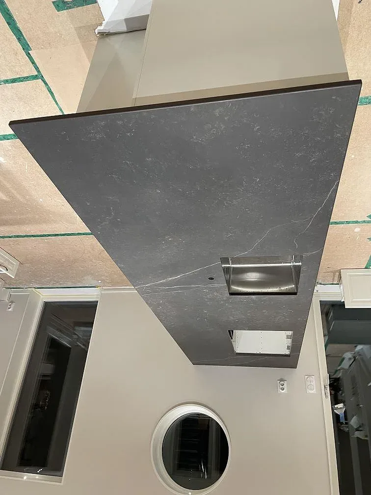 Mörk Dekton Kelya köksbänkskiva med underlimmad rostfri diskho monterad under montering i ett kök i Ljusterö, väggarna ännu klädda med byggpapp.