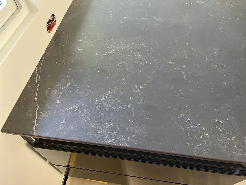 Hörn av köksö i grå Dekton Kelya intill fönstret, matt keramikskiva i ett kök under montering i Löddeköpinge.