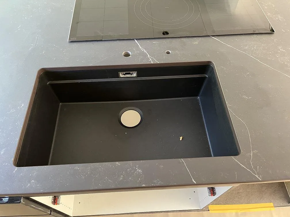 Svart underlimmad kompositdiskho i en köksö av grå Dekton Kelya med separat borrade blandarhål i Löddeköpinge.