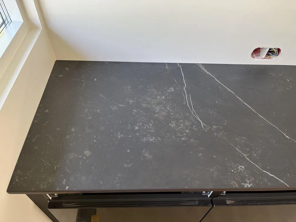 Köksbänkskiva i Dekton Kelya med tydlig grå ådring mot fönstret, matt keramik i ett kök i Löddeköpinge.