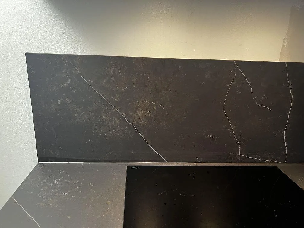 Matt Dekton Kelya som köksbänkskiva och stänkskydd bakom hällen i ett kök i Malmö.