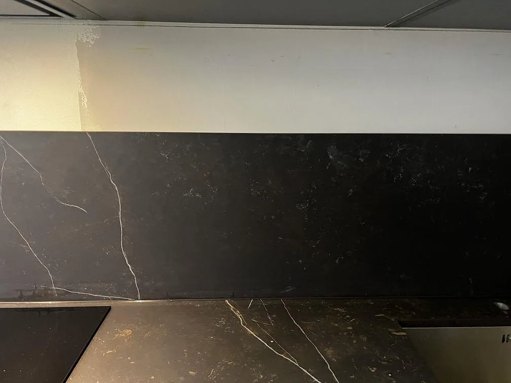 Långt stänkskydd och bänkskiva i mörk matt Dekton Kelya med ljusa ådror i ett kök i Malmö.