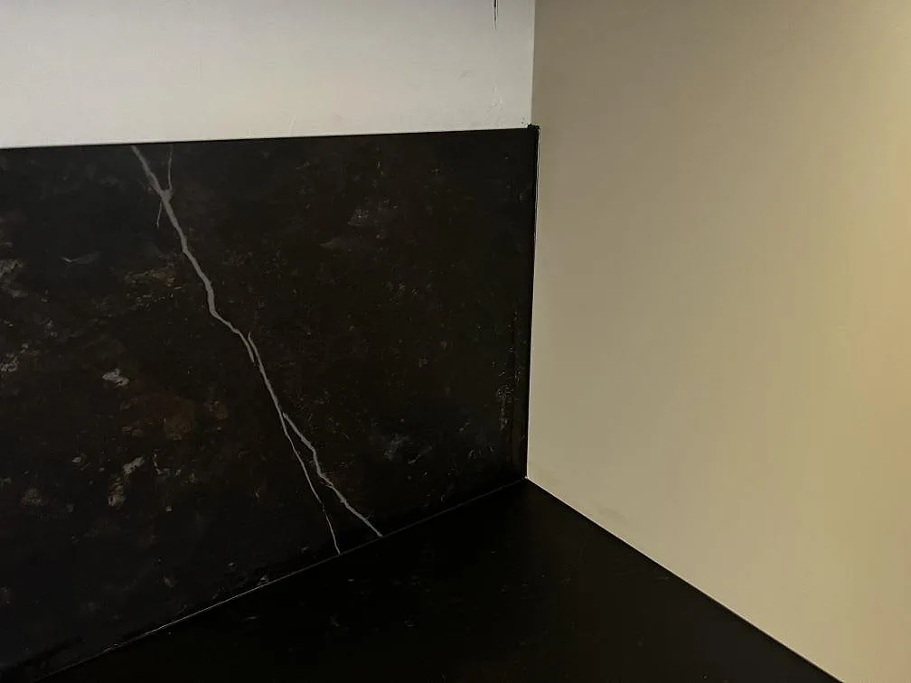Hörnvy av matt Dekton Kelya som bänkskiva och stänkskydd med mörk ådring i Malmö.