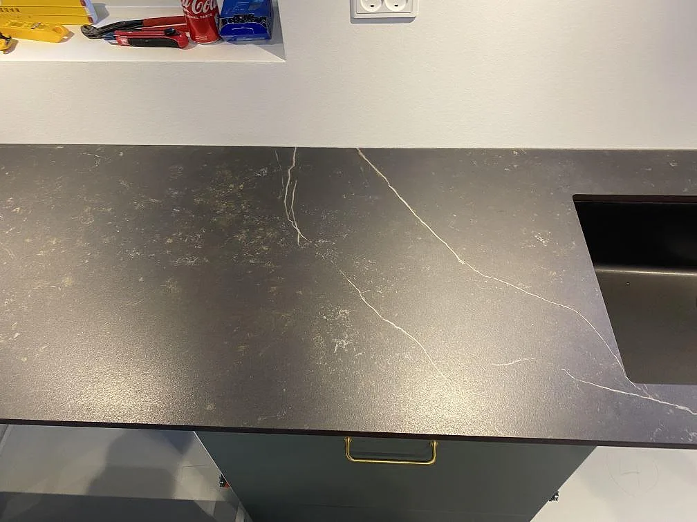 Närbild av matt Dekton Kelya bänkskiva med svart diskho, tunna vita ådror och mörk keramikyta i Ringsted.
