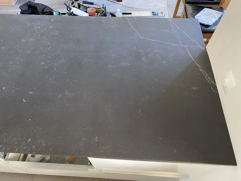 Närbild av den matta köksön i Dekton Kelya med synlig ådring och monteringsverktyg i bakgrunden i Skanör.