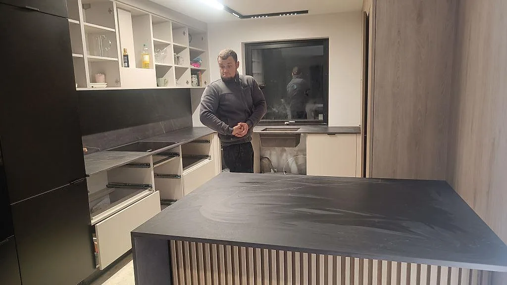 Installerad köksbänkskiva i matt Dekton Kelya med stor ö och mörkt stänkskydd i ett kök i Staffanstorp.