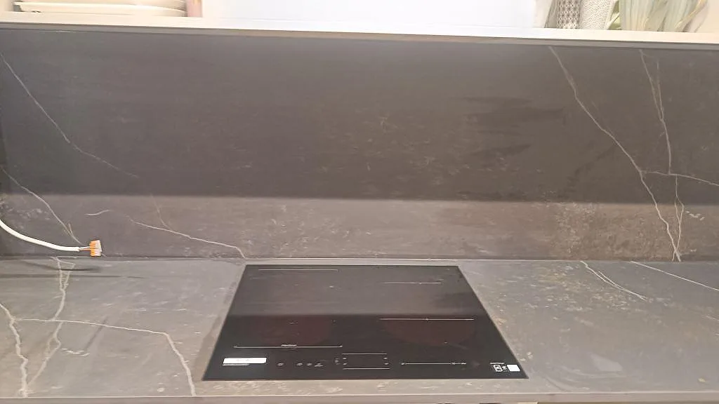 Matt bänkskiva i Dekton Kelya med svart induktionshäll och mörkt stänkskydd i Staffanstorp.