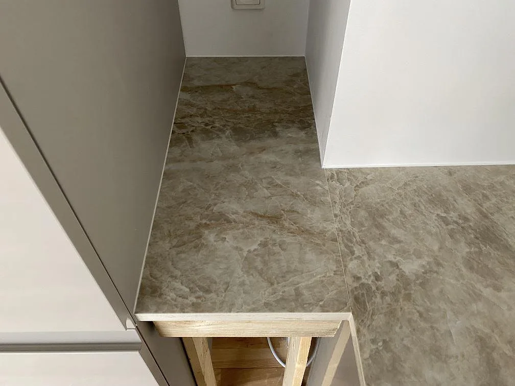 Topvy av L-formad köksbänkskiva i matt Dekton Kelya med grå ådring och öppna stommar i Viby Sjælland.