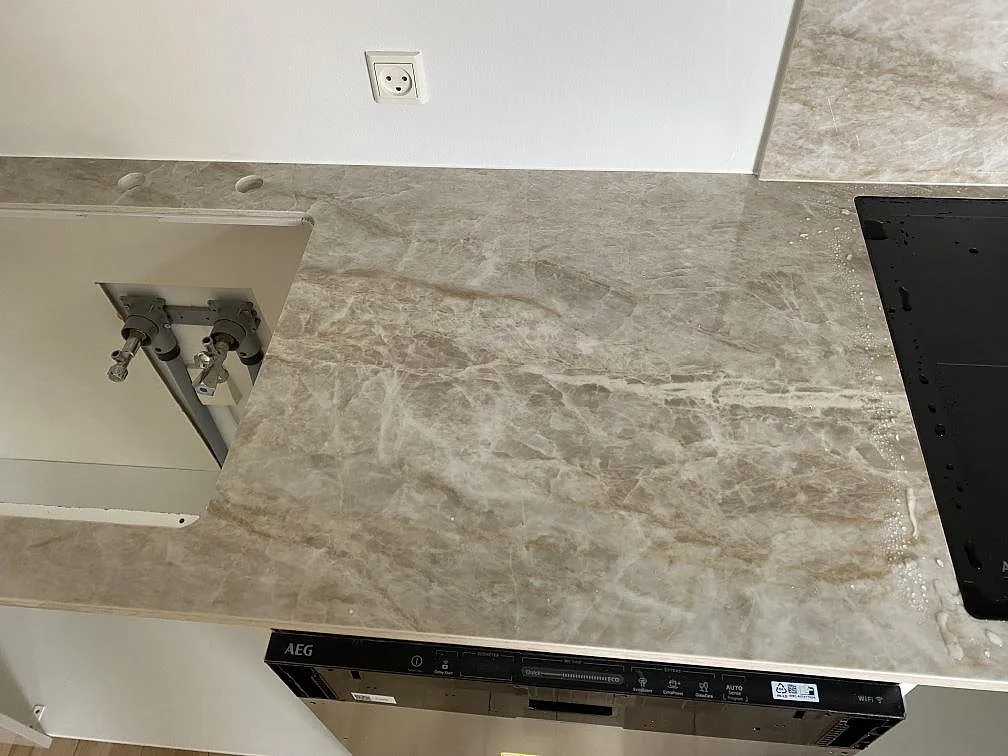 Detalj av köksbänkskiva i matt Dekton Kelya med diskhoöppning, svart häll och stänkskydd under montering i Viby Sjælland.
