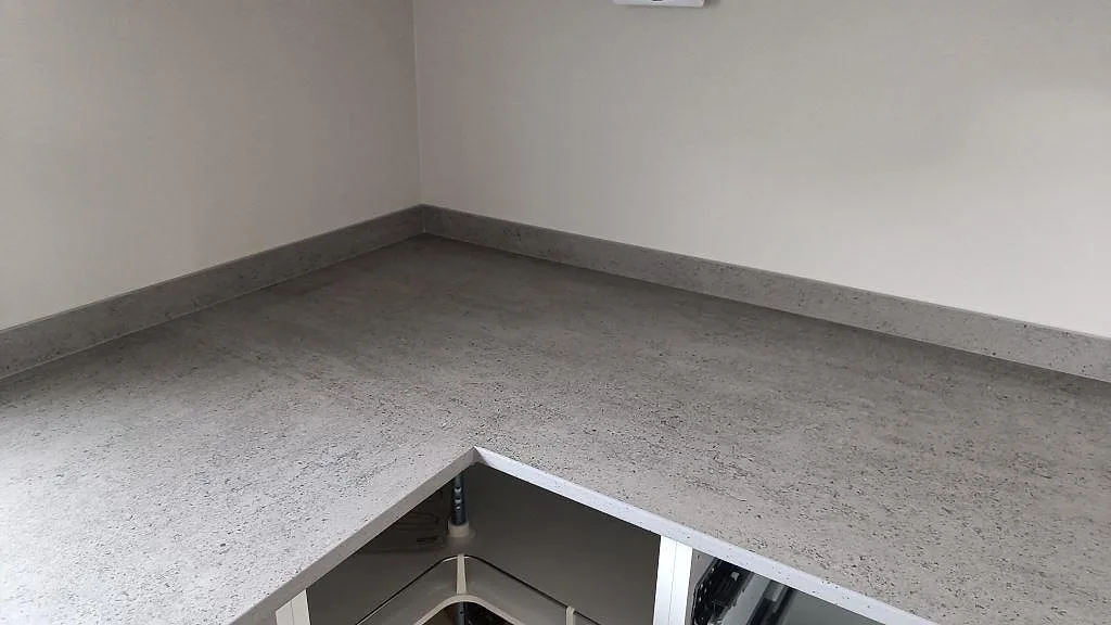 Hörnsektion av köksbänkskiva i matt Dekton Keon keramik med uppvikt stänkkant mot två väggar i Anderstorp.