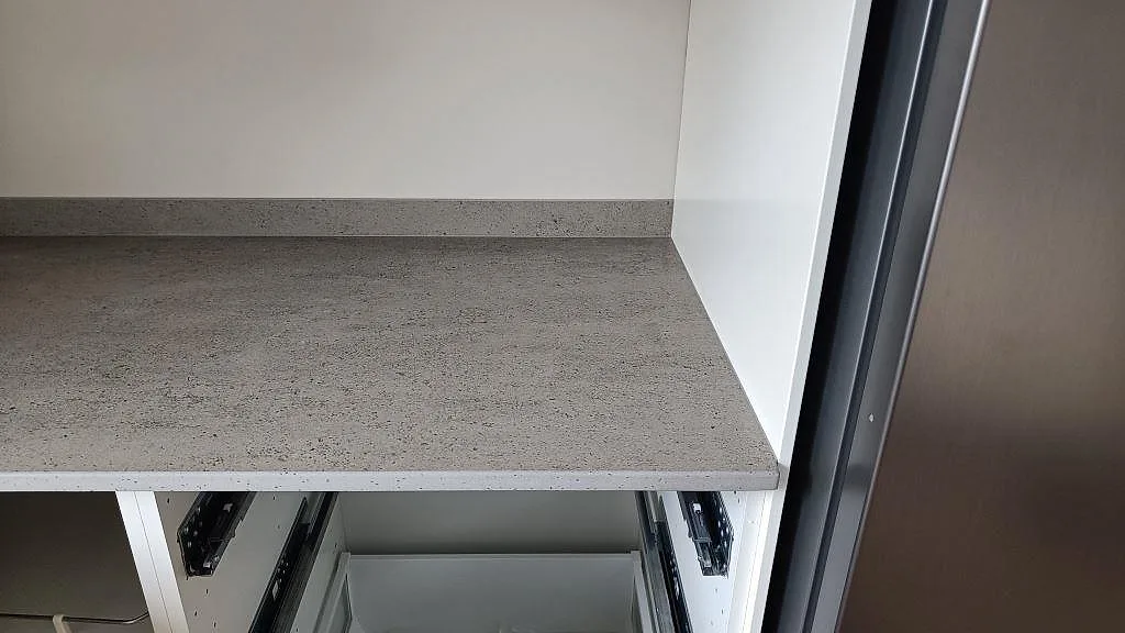 Frontkant och arbetsyta i matt Dekton Keon keramik på vit köksstomme med låg stänkkant i Anderstorp.