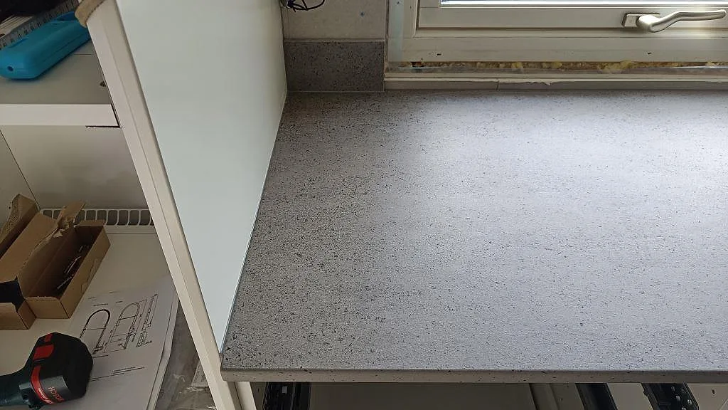 Ytdetalj av matt Dekton Keon köksbänkskiva i keramik under fönster med grå struktur i Anderstorp.