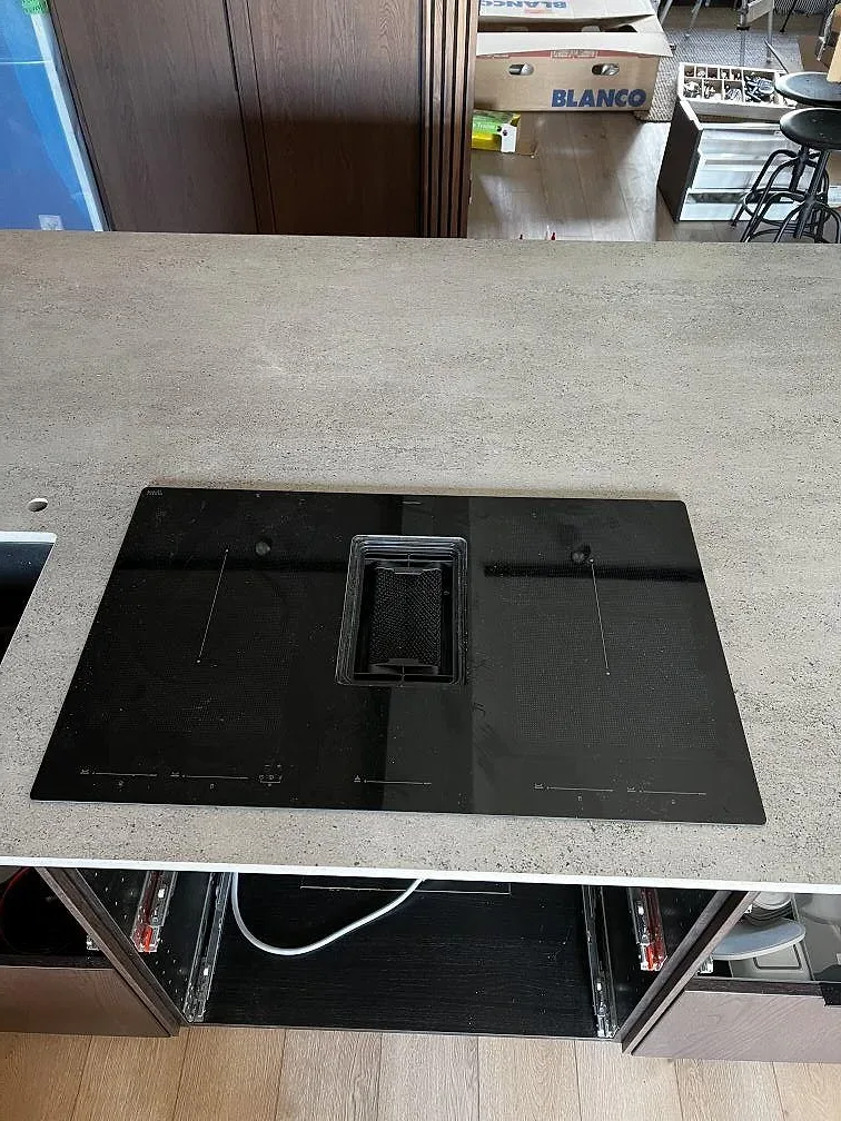 Närbild av matt Dekton Keon i grå keramik med svart induktionshäll monterad i köksbänkskivan i Falkenberg.